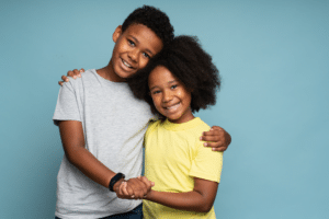Two smiling children standing together with their arms around each other